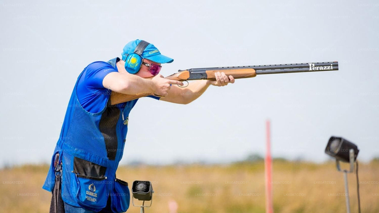 Person in blue protective gear aiming a shotgun in an outdoor setting