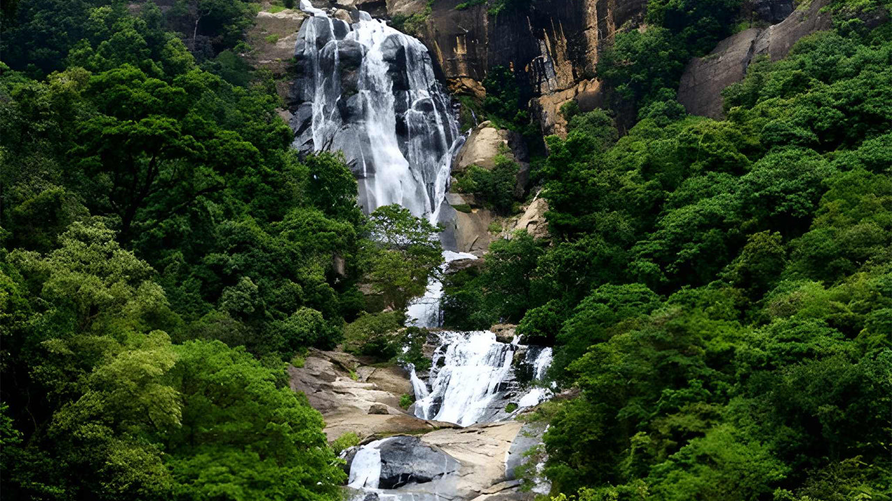 Ravana Waterfall cascading down a rocky cliff surrounded by lush green trees