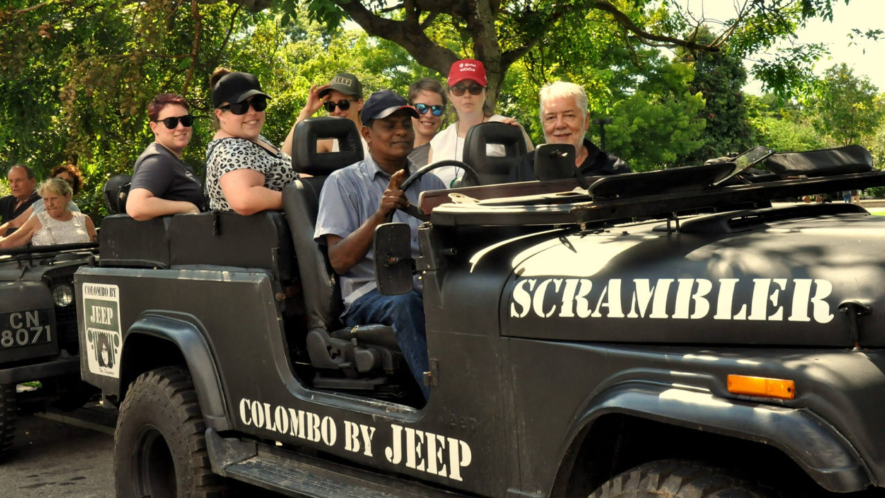 Group of people in a 'Scrambler' Colombo by Jeep vehicle with trees in the background